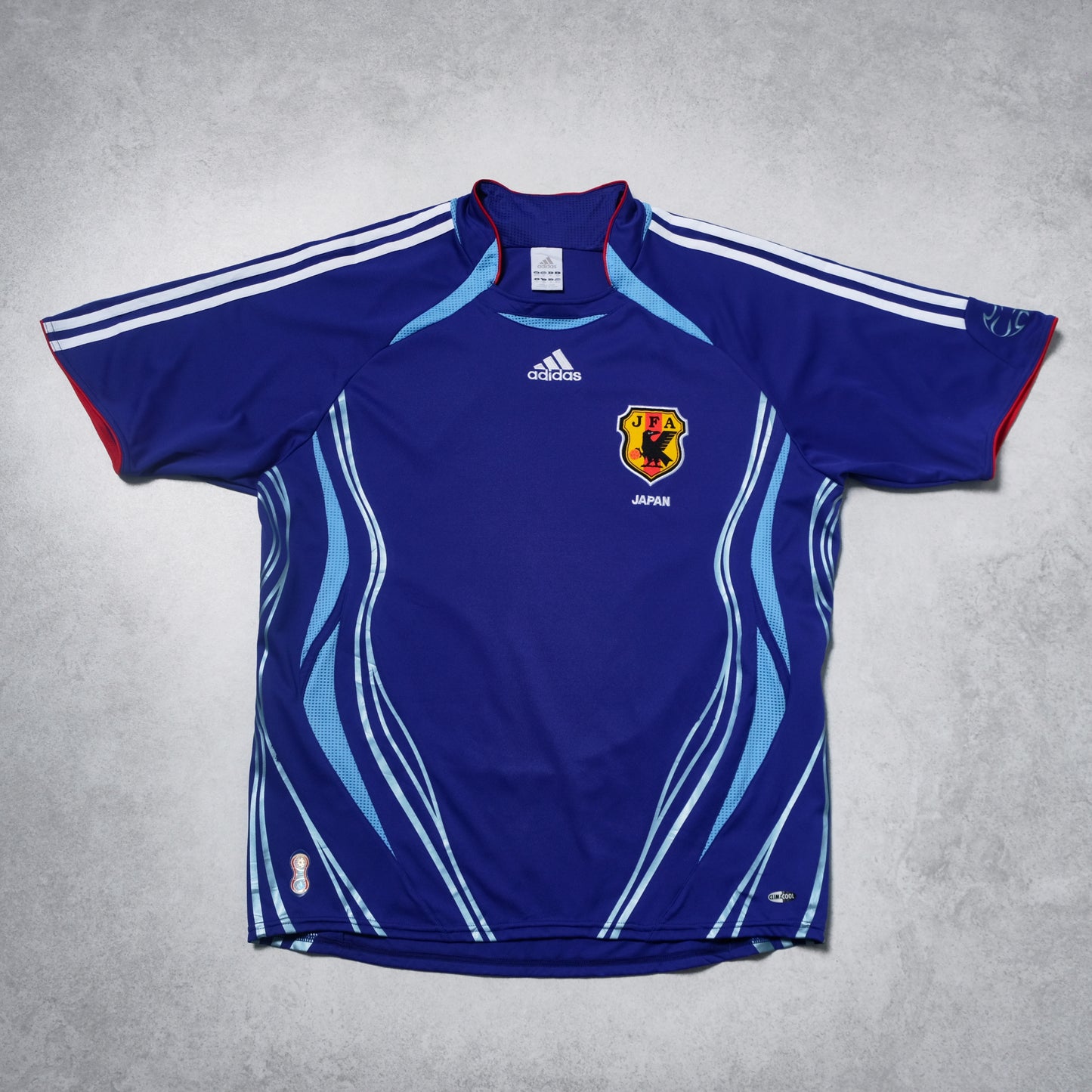 Blue sports jersey with Adidas logo and Japanese flag on a gray background