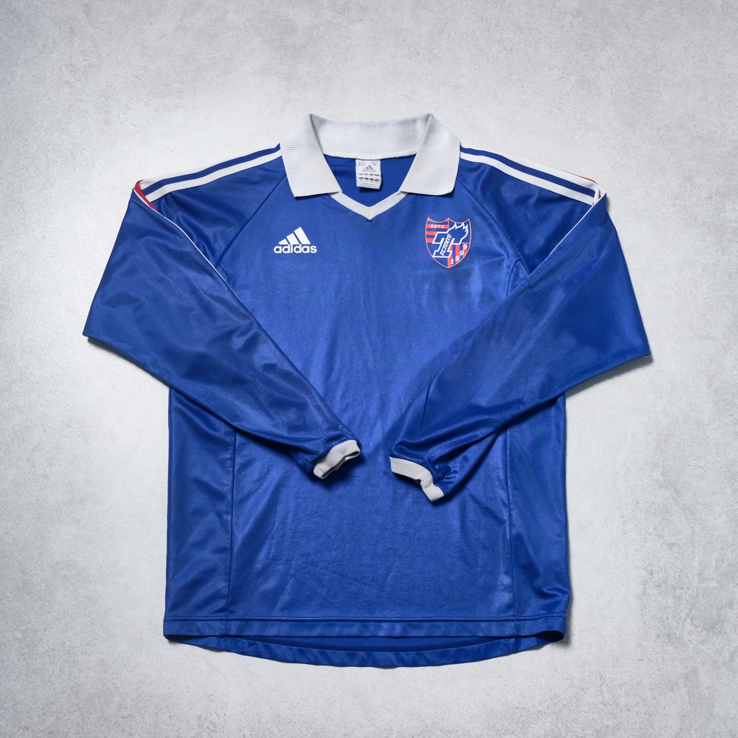 Blue long-sleeve sports jersey with Adidas logo on a gray background
