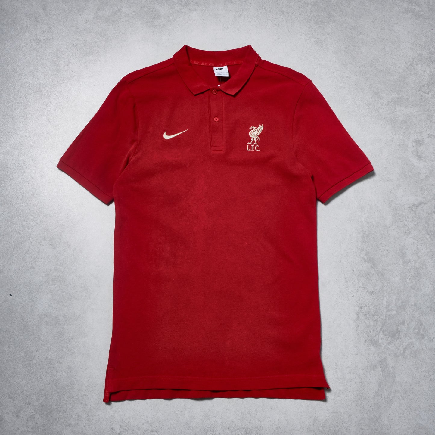 Red polo shirt with Nike and Liverpool FC logos on a gray background