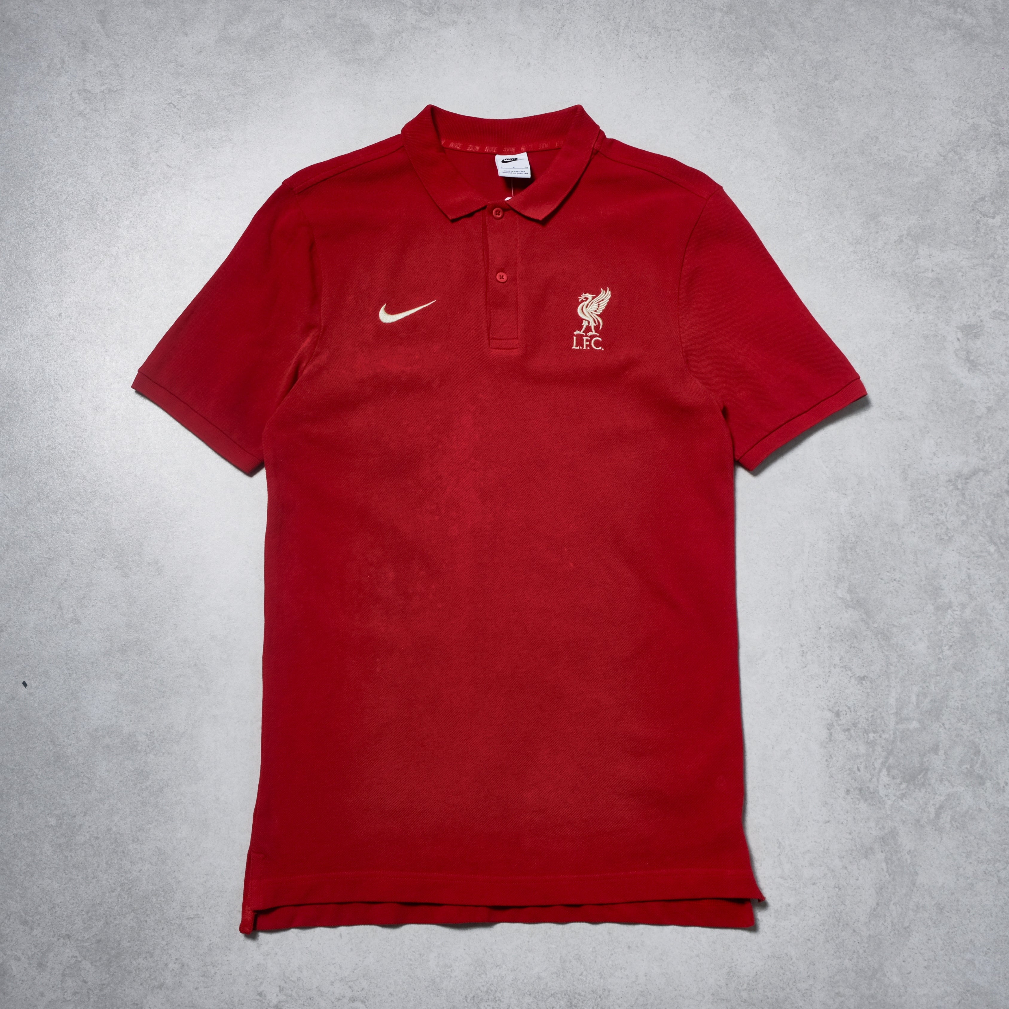 Red polo shirt with Nike and Liverpool FC logos on a gray background