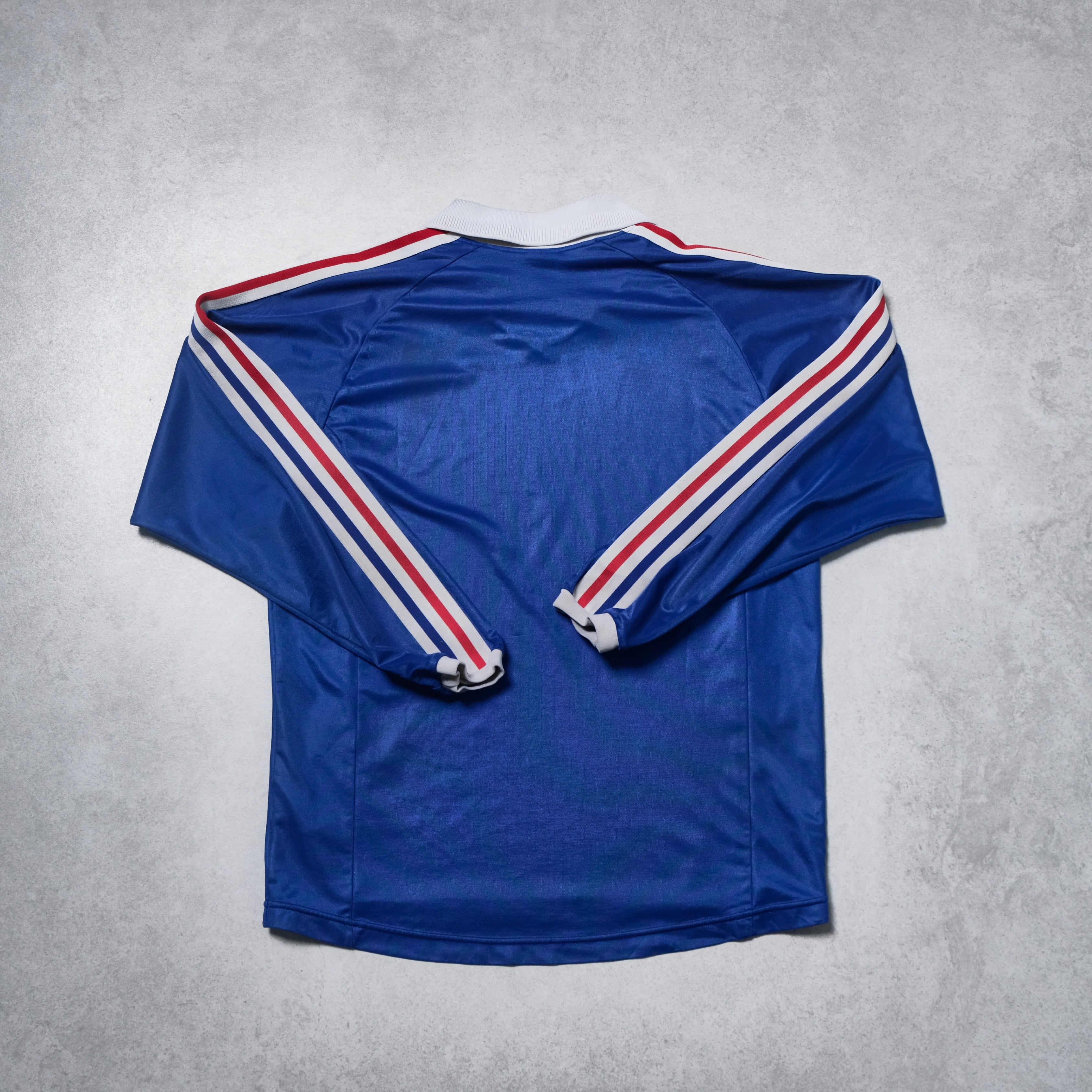 Blue sports jersey with red and white stripes on a gray background