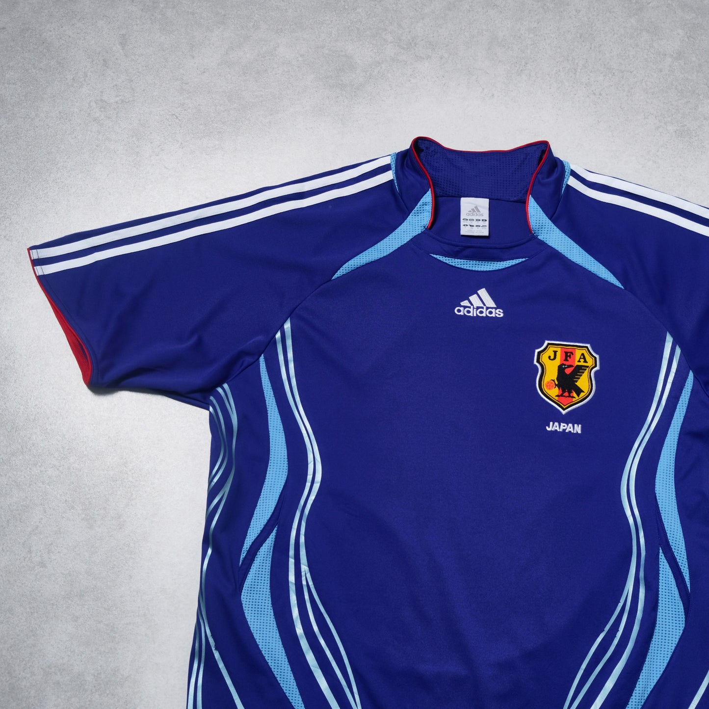 Blue sports jersey with Adidas logo and Japan emblem on a gray background