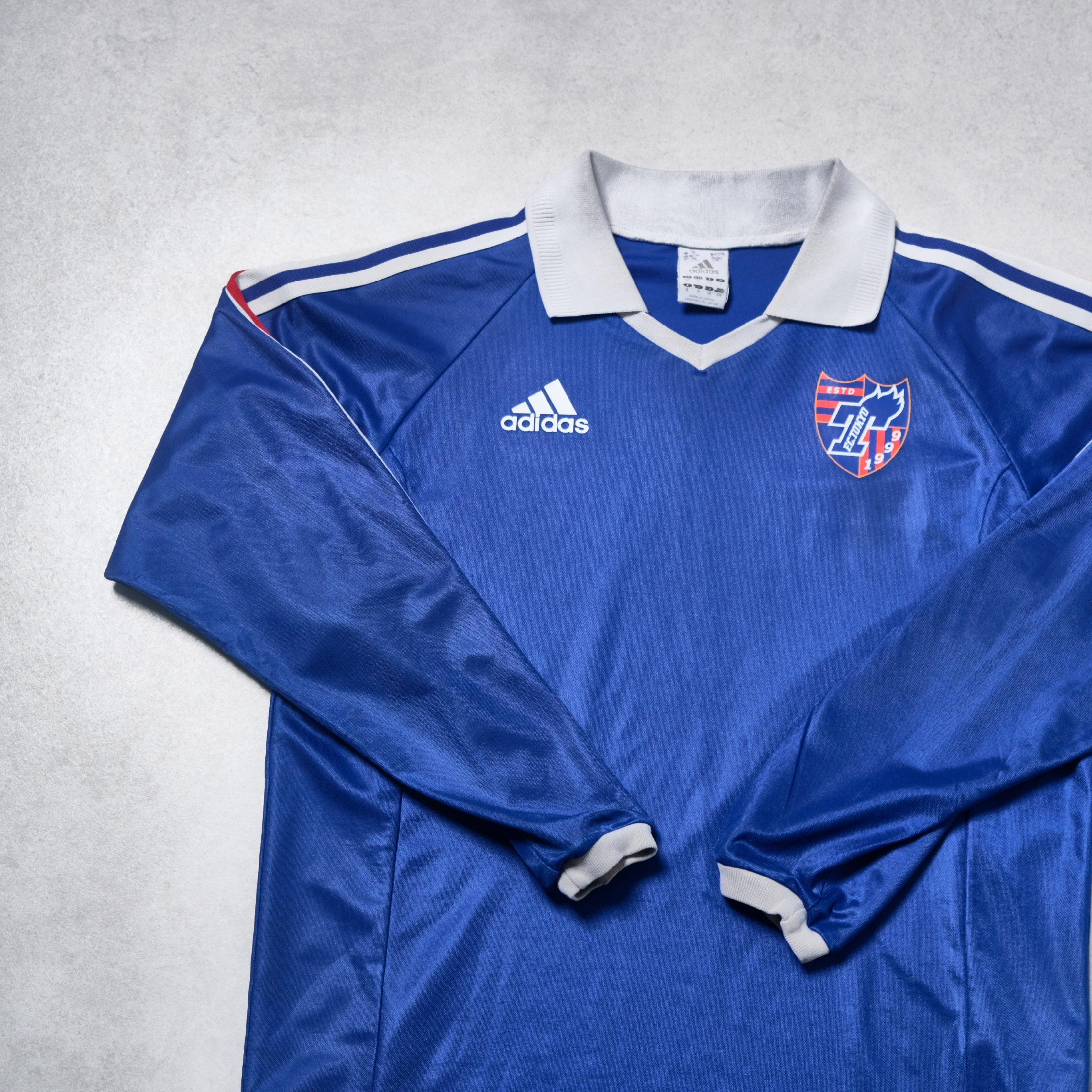 Blue sports jersey with Adidas logo on a gray background