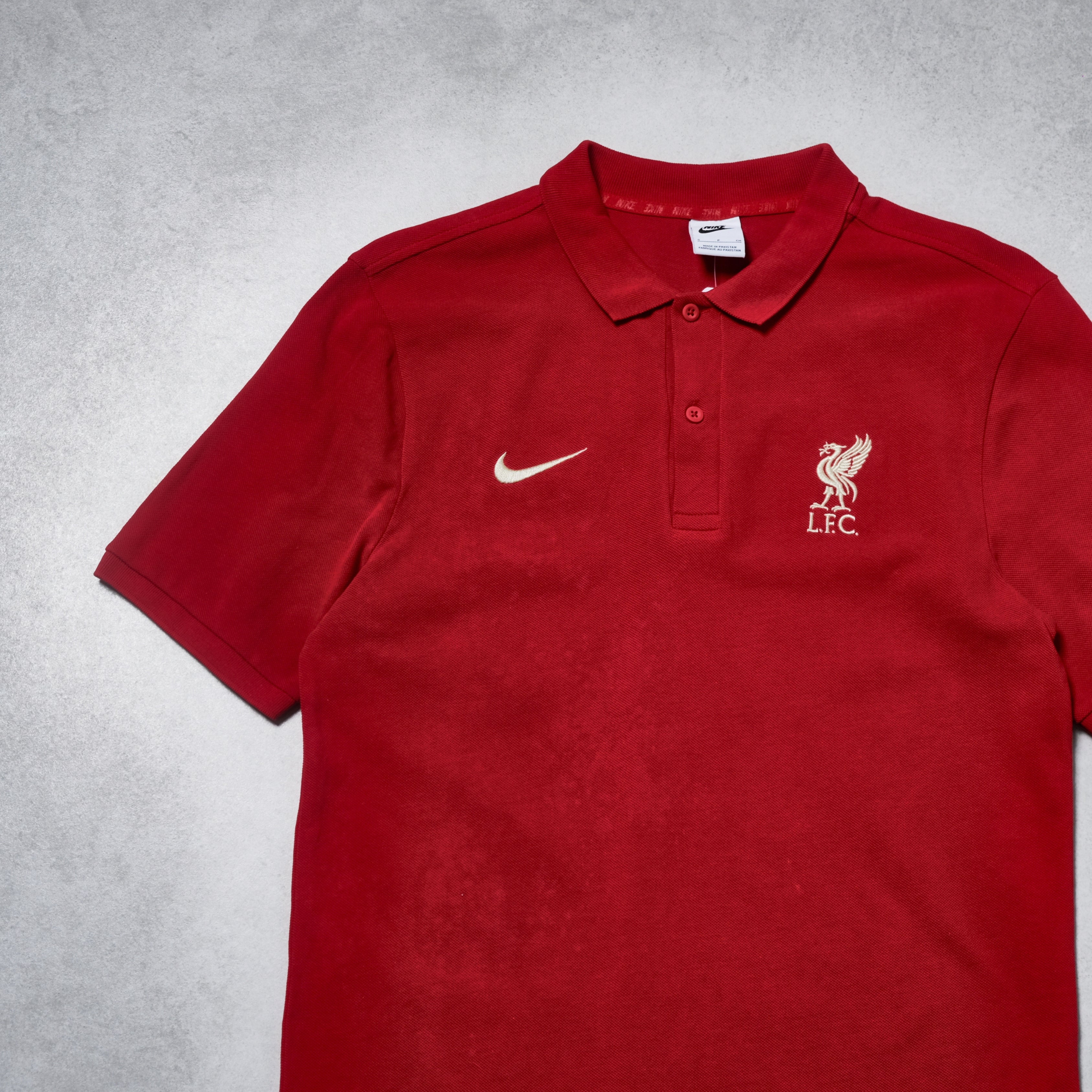 Red polo shirt with Nike and Liverpool FC logos on a gray background